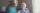 Edlerly man smiles at wife and caretaker.